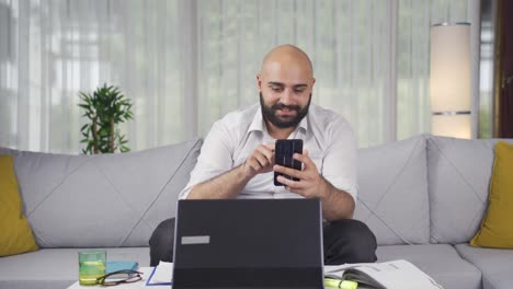 Man-working-from-home-enjoys-mobile-apps-on-phone.